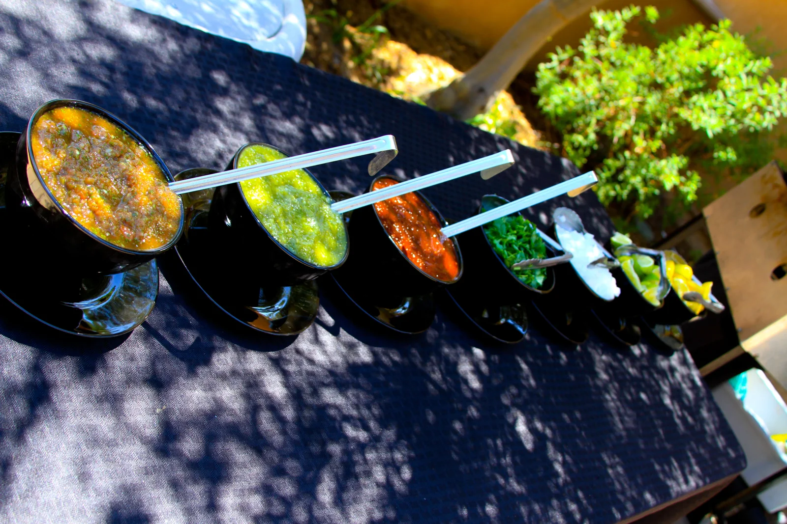 Bowls of fresh salsa and taco toppings on a catering table